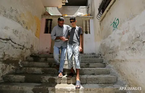 The father of Palestinian blind Saleh Ashour, 16, who lost his sight by Israeli troops during clashes at Gaza-Israel border, helps him to walk in Nusseirat refugee camp in the center of Gaza Strip on July 1, 2018. Photo...