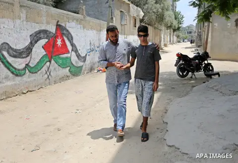 The father of Palestinian blind Saleh Ashour, 16, who lost his sight by Israeli troops during clashes at Gaza-Israel border, helps him to walk in Nusseirat refugee camp in the center of Gaza Strip on July 1, 2018. Photo...
