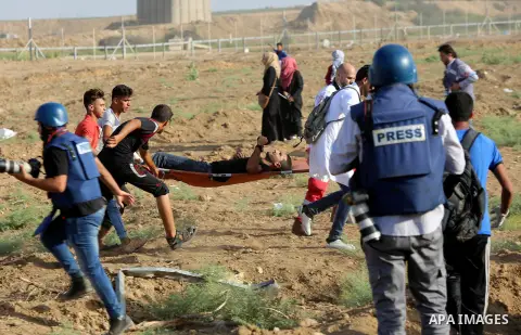 Palestinian Paramedics carry away an injured protester during a protest by Palestinian women where Palestinians demand the right to return to their homeland along the border with Israel east of Gaza City on July 3, 2018....