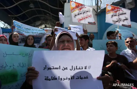 Palestinians hold banners during in a protest against a U.S. decision to cut aid, in front of the headquarters United Nations Relief and Works Agency (UNRWA), in Gaza City on July 4, 2018. Photo by Mahmoud Ajour