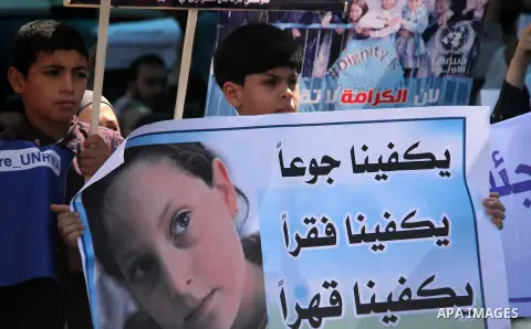 Palestinians hold banners during in a protest against a U.S. decision to cut aid, in front of the headquarters United Nations Relief and Works Agency (UNRWA), in Gaza City on July 4, 2018. Photo by Mahmoud Ajour