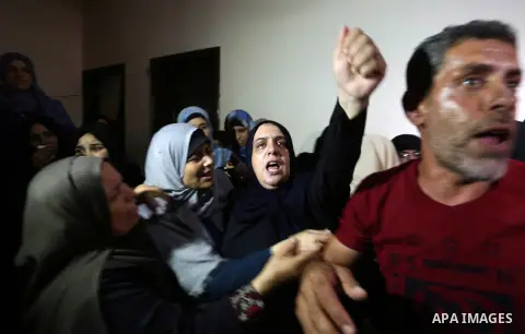 Relatives of Palestinian Mahmoud al-Ghrabli ,16, who died of wounds he sustained during clashes with Israeli troops, mourn during his funeral in Gaza city on July 5, 2018. Photo by Ashraf Amra