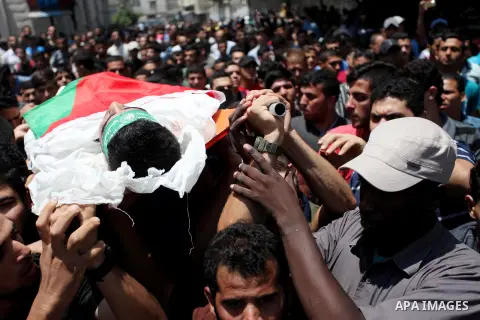 Mourners carry the body of Palestinian Mohammed Abu Halima, 22, who was shot dead by Israeli troops during clashes at Gaza-Israel border, during his funeral in Gaza city on July 7, 2018. Photo by Mahmoud Ajour