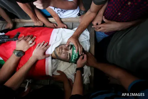 Relatives of Palestinian Mohammed Abu Halima, 22, who was shot dead by Israeli troops during clashes at Gaza-Israel border, mourn over his body at a mosque during his funeral in Gaza city on July 7, 2018. Photo by Mahmou...