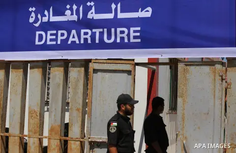 Palestinian policemen stand guard as officials register the passport details of injured Palestinians preparing to board a blockade-running boat, carrying them with other students, out from the Gaza City harbour on July 1...