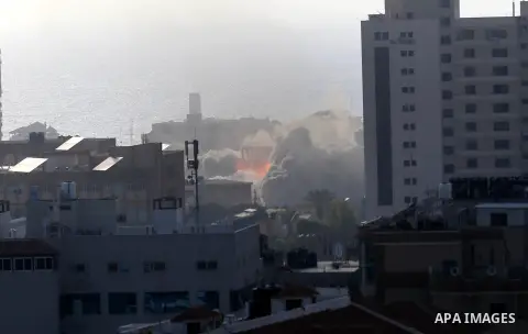 Smoke and fire rises above buildings during an Israeli air strike on Gaza City on July 14, 2018. At least two Palestinians were killed after an Israeli air strike hit an empty building in Gaza City. Photo by Ashraf Amra