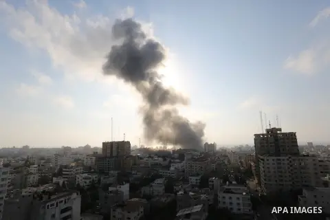 Smoke rises above buildings during an Israeli air strike on Gaza City on July 14, 2018. At least two Palestinians were killed after an Israeli air strike hit an empty building in Gaza City. Photo by Ashraf Amra