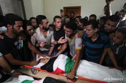 Relatives of two Palestinians, who were killed in an Israeli air strike, mourn over their bodies during their funeral at a mosque in Gaza city on July 15, 2018. Photo by Mahmoud Ajour