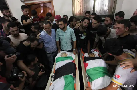 Relatives of two Palestinians, who were killed in an Israeli air strike, mourn over their bodies during their funeral at a mosque in Gaza city on July 15, 2018. Photo by Mahmoud Ajour
