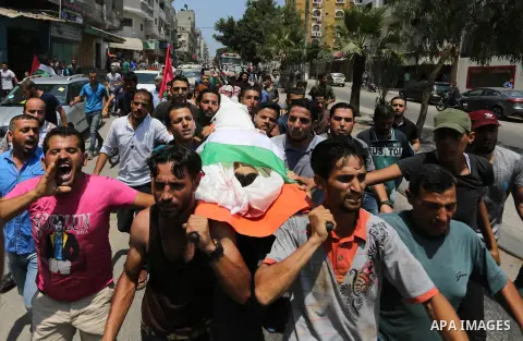 Mourners carry the body of Palestinian Louay Kahil, who was killed in an Israeli air strike, during his funeral in Gaza city on July 15, 2018. Photo by Ashraf Amra