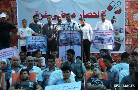 Ashraf al-Qudra, a spokesman for the health ministry in Gaza strip, speaks a press conference, while Palestinians who were wounded by Israeli troops during clashes at Israeli-Gaza border, take part in a protest to demand...