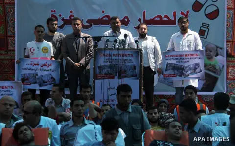 Ashraf al-Qudra, a spokesman for the health ministry in Gaza strip, speaks a press conference, while Palestinians who were wounded by Israeli troops during clashes at Israeli-Gaza border, take part in a protest to demand...