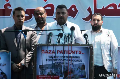 Ashraf al-Qudra, a spokesman for the health ministry in Gaza strip, speaks a press conference, while Palestinians who were wounded by Israeli troops during clashes at Israeli-Gaza border, take part in a protest to demand...