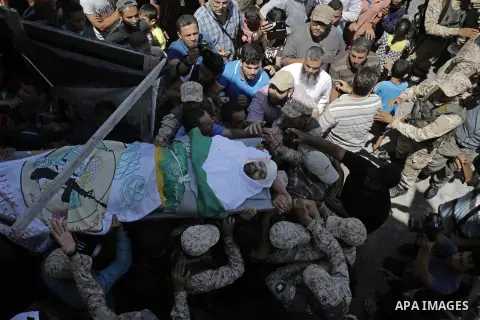 Mourners carry the body of Palestinian Abdul Karim Radwan, who was killed in an Israeli air strike, during his funeral in Rafah in the southern of Gaza Strip July 20, 2018. Photo by Ashraf Amra