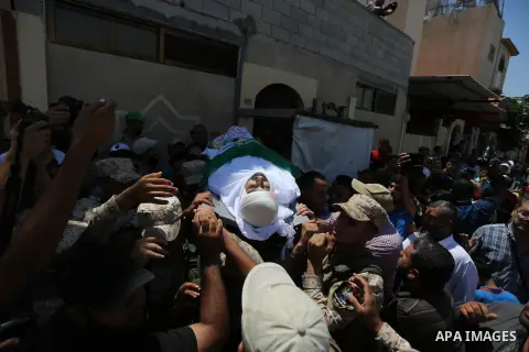 Mourners carry the body of Palestinian Abdul Karim Radwan, who was killed in an Israeli air strike, during his funeral in Rafah in the southern of Gaza Strip July 20, 2018. Photo by Ashraf Amra
