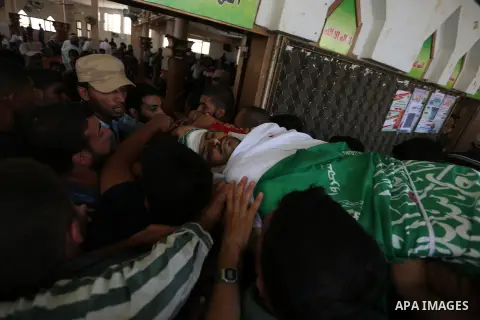 Mourners carry the body of Palestinian militant Mohammed Abu Dakah, 31, who was killed in an Israeli strike, during his funeral in Khan Younis in the southern of Gaza Strip, on July 21, 2018. Photo by Ashraf Amra
