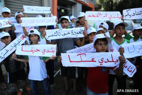 Palestinian children hold banners during in a protest against the continued Israeli siege on the Gaza Strip, in Gaza city on July 22, 2018. Photo by Ashraf Amra