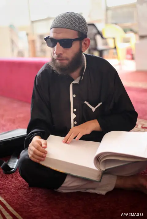 A Palestinian blind boy reads and memorise the holy Quran in braille at Dar al-Quran and Sunnah in Gaza city, on July 23, 2018. Photo by Mahmoud Ajour
