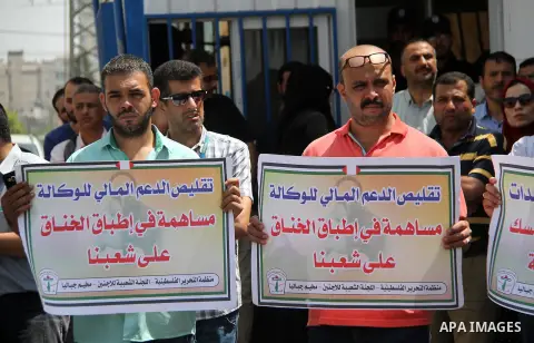 Palestinian employees of United Nations Relief and Works Agency (UNRWA) hold a sign during a protest against a U.S. decision to cut aid, in front of the headquarters UNRWA, in Gaza City on July 24, 2018. Photo by Mahmoud...