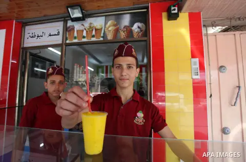 Palestinian vendors sell ice-cream (sundae) to customers during a heatwave in Gaza city on July 25, 2018. Photo by Mahmoud Ajour