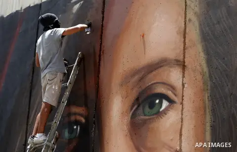 Italian artist Jorit Agoch paints a mural depicting Palestinian teenager Ahed Tamimi on Israel's controversial separation barrier in the West Bank city of Bethlehem, on July 25,2018. Tamimi, was charged earlier this year...