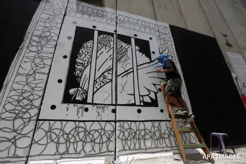 Italian artist Jorit Agoch paints a mural depicting Palestinian teenager Ahed Tamimi on Israel's controversial separation barrier in the West Bank city of Bethlehem, on July 25,2018. Tamimi, was charged earlier this year...