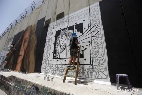 Italian artist Jorit Agoch paints a mural depicting Palestinian teenager Ahed Tamimi on Israel's controversial separation barrier in the West Bank city of Bethlehem, on July 25,2018. Tamimi, was charged earlier this year...