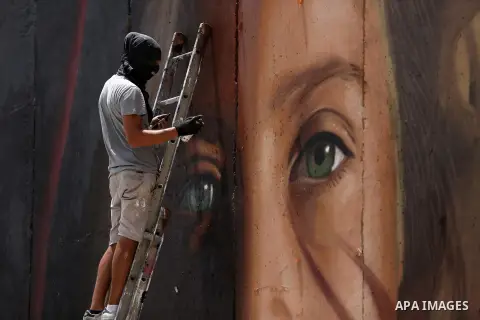 Italian artist Jorit Agoch paints a mural depicting Palestinian teenager Ahed Tamimi on Israel's controversial separation barrier in the West Bank city of Bethlehem, on July 25,2018. Tamimi, was charged earlier this year...