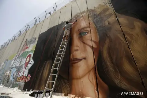 Italian artist Jorit Agoch paints a mural depicting Palestinian teenager Ahed Tamimi on Israel's controversial separation barrier in the West Bank city of Bethlehem, on July 25,2018. Tamimi, was charged earlier this year...