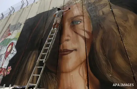 Italian artist Jorit Agoch paints a mural depicting Palestinian teenager Ahed Tamimi on Israel's controversial separation barrier in the West Bank city of Bethlehem, on July 25,2018. Tamimi, was charged earlier this year...