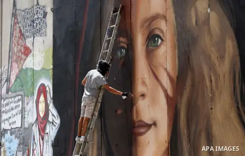 Italian artist Jorit Agoch paints a mural depicting Palestinian teenager Ahed Tamimi on Israel's controversial separation barrier in the West Bank city of Bethlehem, on July 25,2018. Tamimi, was charged earlier this year...