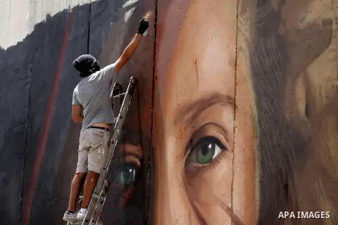 Italian artist Jorit Agoch paints a mural depicting Palestinian teenager Ahed Tamimi on Israel's controversial separation barrier in the West Bank city of Bethlehem, on July 25,2018. Tamimi, was charged earlier this year...