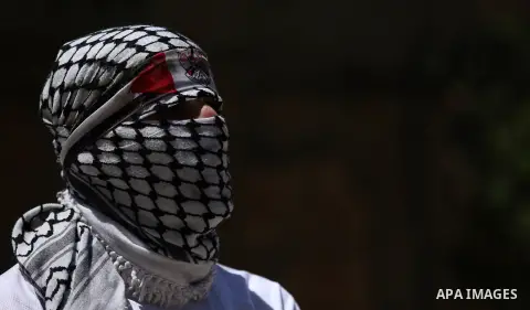 A masked Palestinian protester looks on during clashes with Israeli troops following a demonstration against the expropriation of Palestinian land by Israel in the village of Kfar Qaddum, near Nablus, in the occupied Wes...