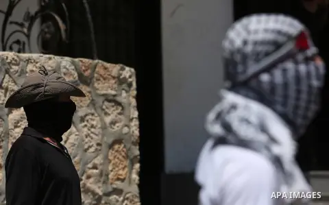 Masked Palestinian protesters look on during clashes with Israeli troops following a demonstration against the expropriation of Palestinian land by Israel in the village of Kfar Qaddum, near Nablus, in the occupied West...