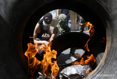 Palestinian protesters burn tyres during clashes following a demonstration, in the West Bank city of Hebron, on July 27, 2018. Photo by Wisam Hashlamoun