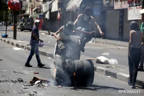 Palestinian protesters burn tyres during clashes following a demonstration, in the West Bank city of Hebron, on July 27, 2018. Photo by Wisam Hashlamoun