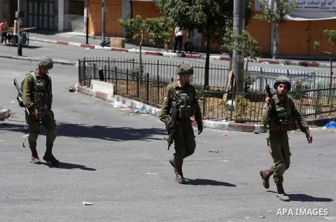 Israeli troops take position during clashes with Palestinian protesters in the West Bank city of Hebron on July 27, 2018. Photo by Wisam Hashlamoun