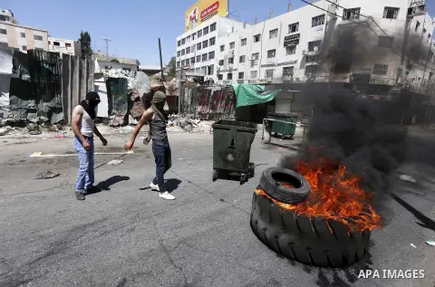 Palestinian protesters burn tyres during clashes following a demonstration, in the West Bank city of Hebron, on July 27, 2018. Photo by Wisam Hashlamoun