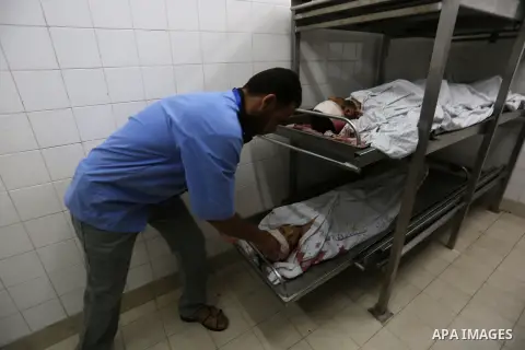 A medic stands over the bodies of 11-year-old Majdi Al-Sutari and 43-year-old Ghazi Abu Mustafa, who were killed during a demonstration along the border between Israel and the Gaza strip, at the morgue of the European Ho...