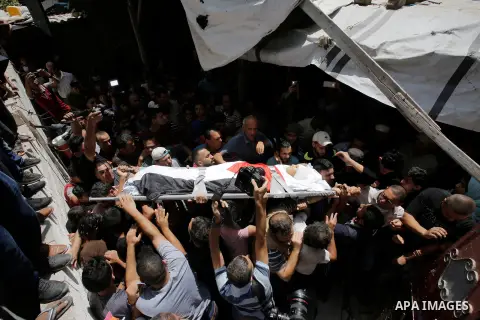 Mourners carry the body of Majdi al-Sutari, 11, who was shot dead by Israeli troops during clashes along the border the previous day, during his funeral in Rafah in the southern Gaza Strip on July 28, 2018. Photo by Rama...