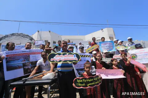 Palestinians hold banners during a protest to demand the built of a hospital in Rafah in the southern Gaza strip on Aug. 01, 2018. Photo by Mahmoud Khattab