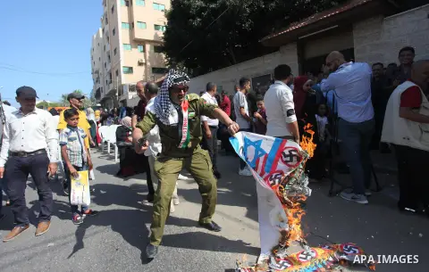 Palestinians burn an Israeli, British and U.S. flags during a protest to show solidarity with Palestinian prisoners held in Israeli jails, in front of Red cross office in Gaza city on August 6, 2018. Photo by Mahmoud Ajo...