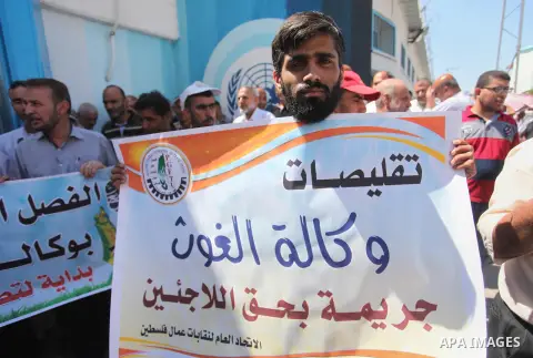 Palestinians hold banners during a protest against a U.S. decision to cut aid, in front of the headquarters United Nations Relief and Works Agency (UNRWA), in Gaza City, on August 6, 2018. Photo by Mahmoud Ajour