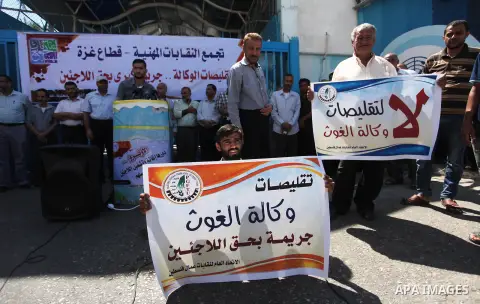 Palestinians hold banners during a protest against a U.S. decision to cut aid, in front of the headquarters United Nations Relief and Works Agency (UNRWA), in Gaza City, on August 6, 2018. Photo by Mahmoud Ajour