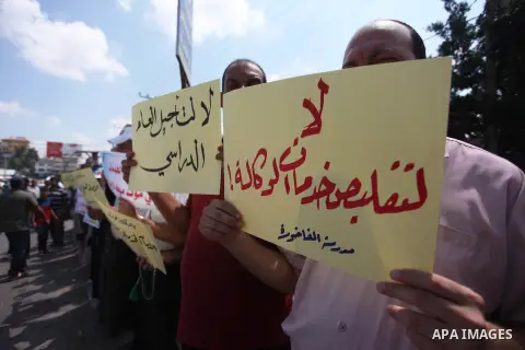 Palestinians hold banners during a protest against a U.S. decision to cut aid in Jabalia in the northern of Gaza Strip on August 7, 2018. Photo by Mahmoud Ajour