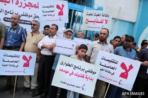 Palestinians hold placards during a protest a against the decision of United Nations Relief and Works Agency (UNRWA) reducing its services and job cuts announced by the agency, and calling for the start of the new school...