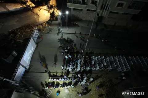 Palestinians watch a movie on large screen next to the rubble of Said al-Mishal Cultural Center which was destroyed by an Israeli air strike in Gaza city on Aug. 14, 2018. Photo by Mahmoud Ajour