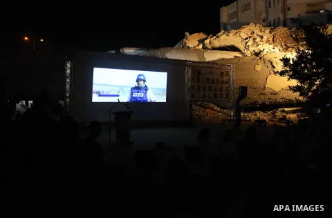 Palestinians watch a movie on large screen next to the rubble of Said al-Mishal Cultural Center which was destroyed by an Israeli air strike in Gaza city on Aug. 14, 2018. Photo by Mahmoud Ajour