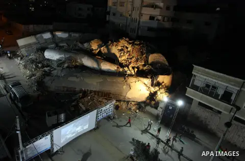 Palestinians watch a movie on large screen next to the rubble of Said al-Mishal Cultural Center which was destroyed by an Israeli air strike in Gaza city on Aug. 14, 2018. Photo by Mahmoud Ajour