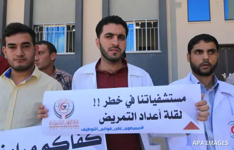 Palestinian Nurses hold banners during a protest to demand their rights, in Gaza city, on August 15, 2018. Photo by Mahmoud Khattab